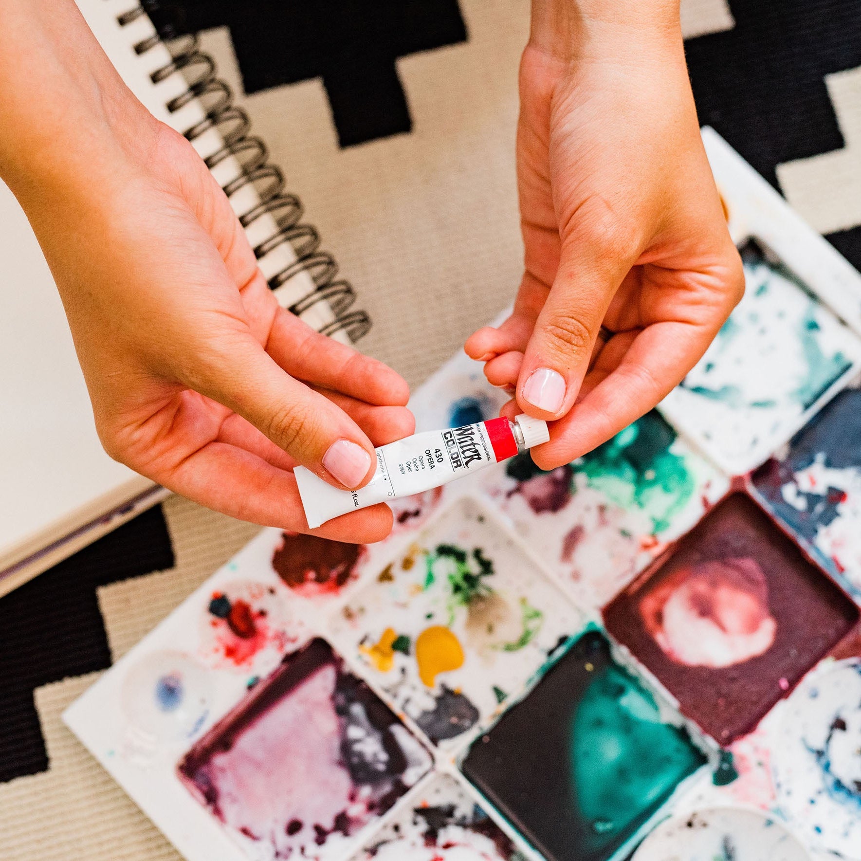 pittsburgh watercolor artist holding watercolor paints over paint palette  